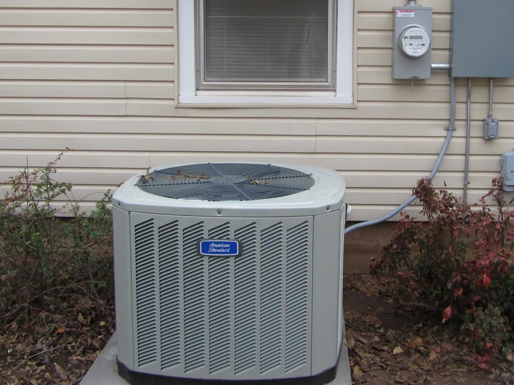An American Standard air conditioner condenser beside a house