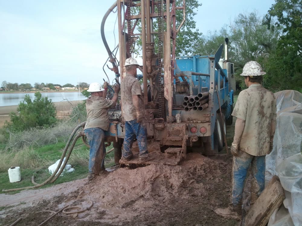 A crew drilling a geothermal loop beside a lake