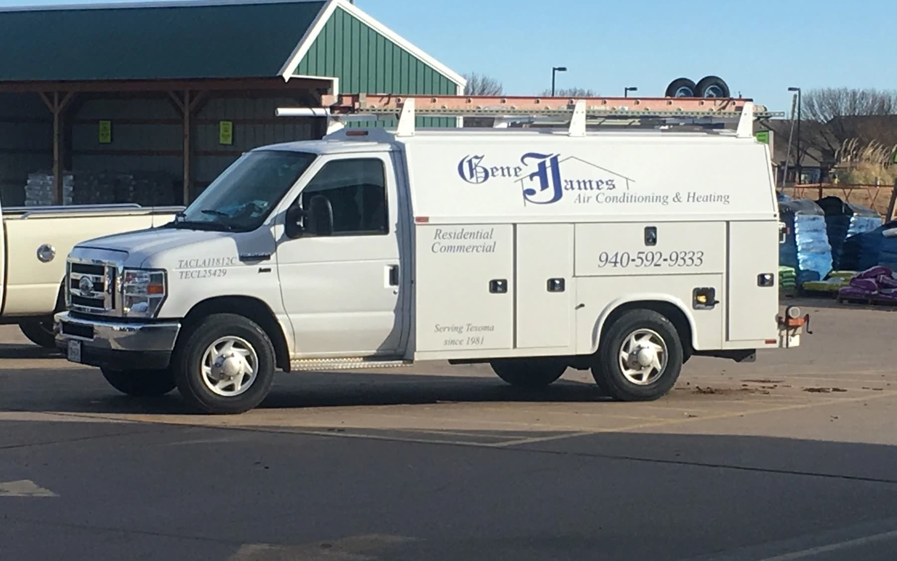 A white Gene James Air Conditioning and Heating service van parked in a lot, with the phone number on the door